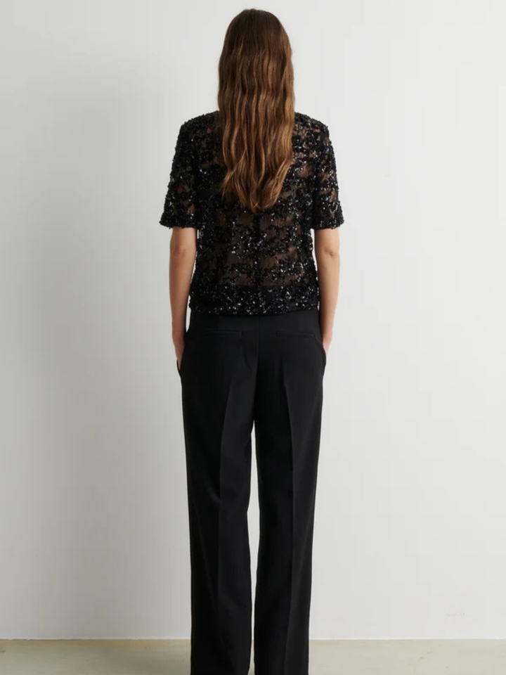 Second Female sort bluse i semitransparent blondemesh med glitrende pailletter og perler, korte ærmer, regular pasform og knaplukning bagpå.