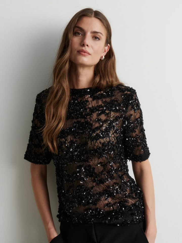 Second Female sort bluse i semitransparent blondemesh med glitrende pailletter og perler, korte ærmer, regular pasform og knaplukning bagpå.